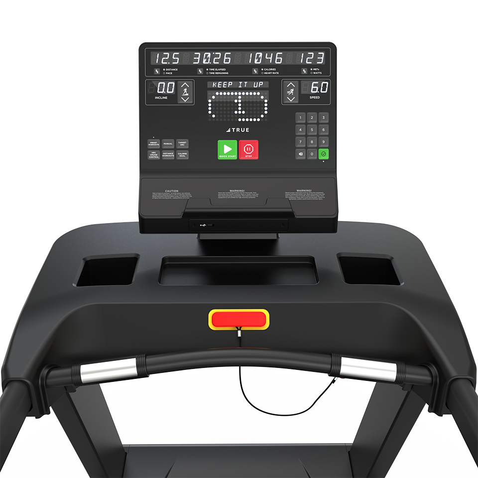 Close-up of a treadmill control panel displaying speed, distance, calories, heart rate, and time. A KEEP IT UP message appears onscreen. The treadmill has cup holders and a safety key with a red cord.