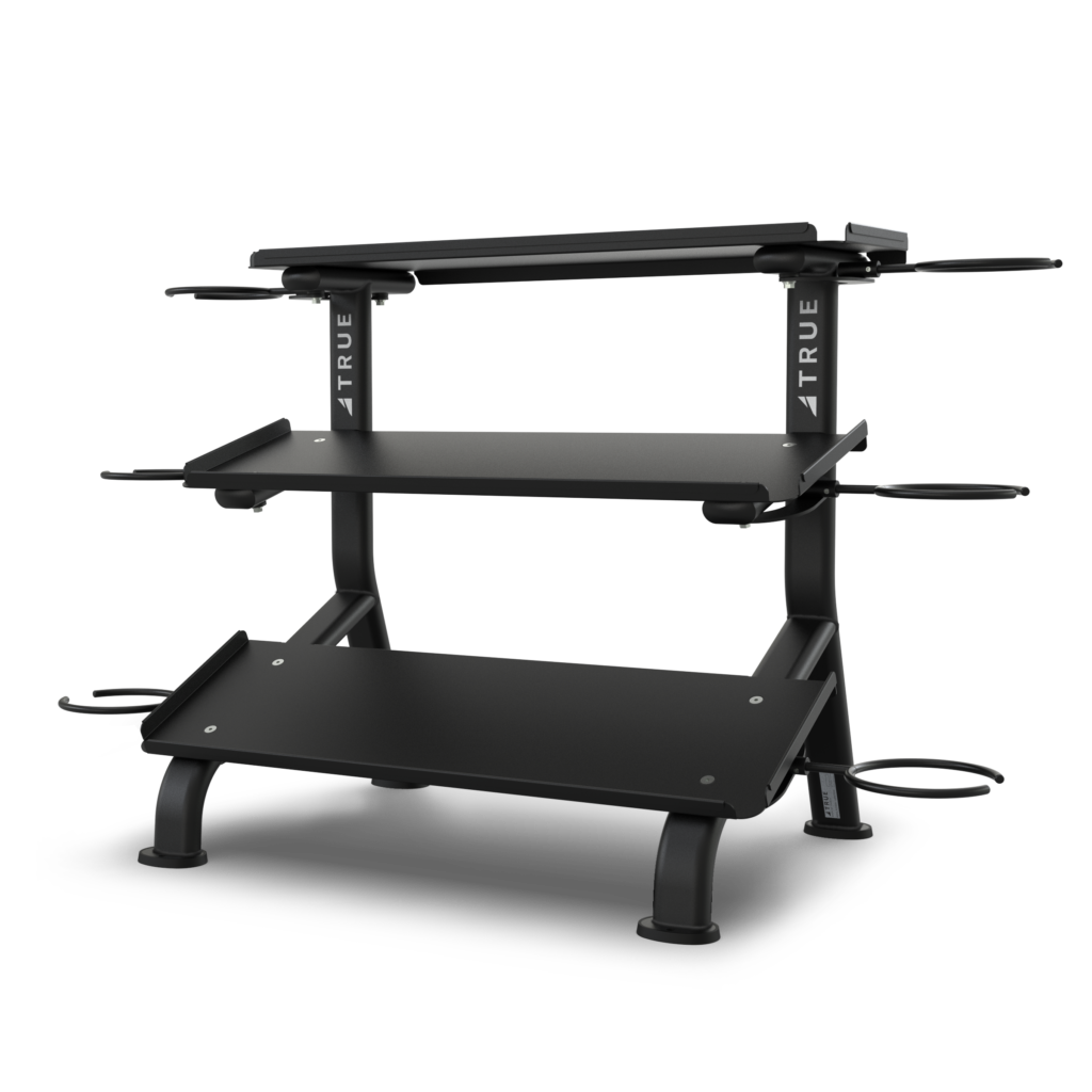 Black, two-tiered gym equipment rack with sturdy legs, raised top shelf, and side hooks for accessories, designed for organizing weights or fitness gear against a plain white background.
