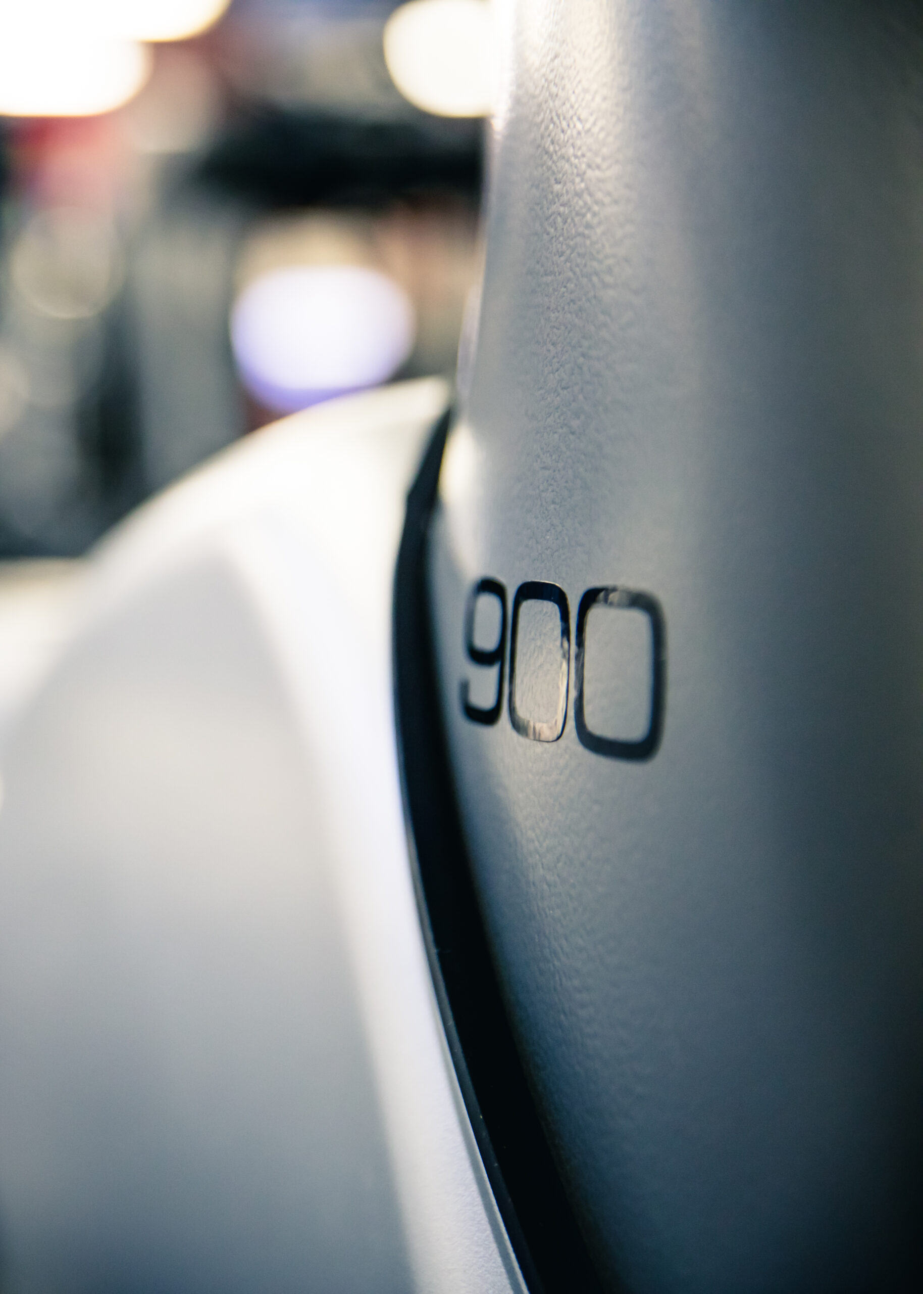 Close-up of a smooth gray surface with the number 900 printed on it in black, possibly part of a vehicle or equipment, with a blurred background.