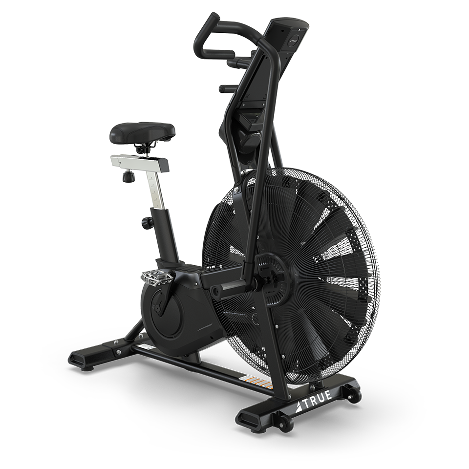 A black stationary air bike with a large fan wheel, adjustable seat, and handlebars, designed for indoor exercise. The bike has sturdy footrests and pedals, and the brand name TRUE is visible on the frame.