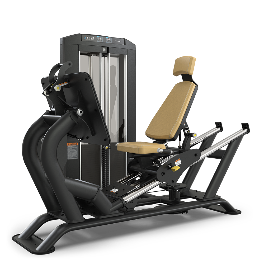 A black and tan leg press machine stands on a white background, featuring a padded seat with back and head support, adjustable weights, and foot platform for strength training exercises.