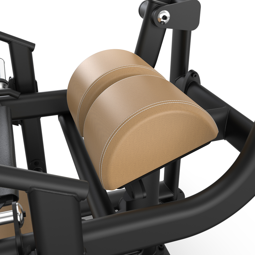 Close-up view of a fitness machine with a padded, tan-colored support cushion and black metal frame, designed for exercises such as leg curls or extensions. The cushion has white stitching for added detail.