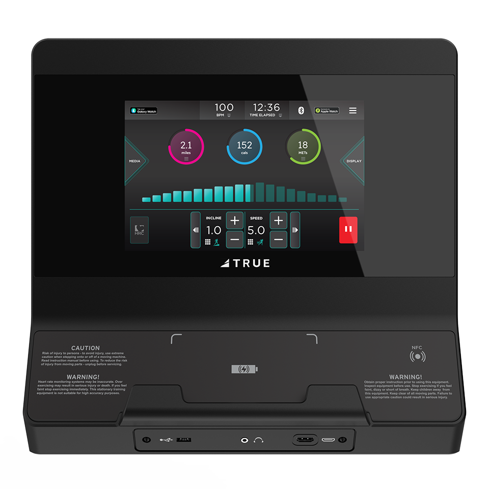 A black treadmill console with a touchscreen display showing workout metrics, speed, incline, media options, and control buttons. The brand TRUE is visible below the screen.