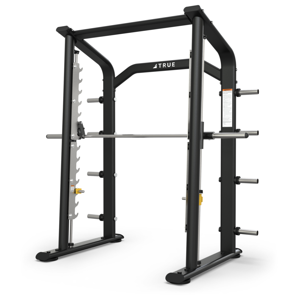 A black and silver Smith machine with a barbell and weight storage pegs, designed for weightlifting exercises; the brand TRUE is visible at the top center of the frame.