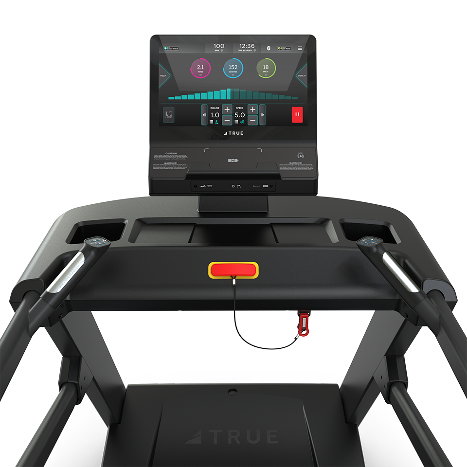 A close-up view of a treadmill console displaying workout metrics on a digital screen, with a safety key and red clip attached just below the display.