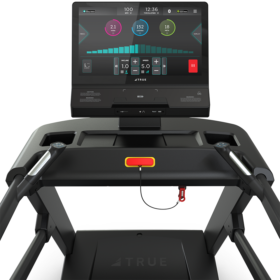 Close-up of a treadmill console displaying workout data, including heart rate, time, and distance. The screen shows colorful graphs and stats, with a safety key attached below the display.