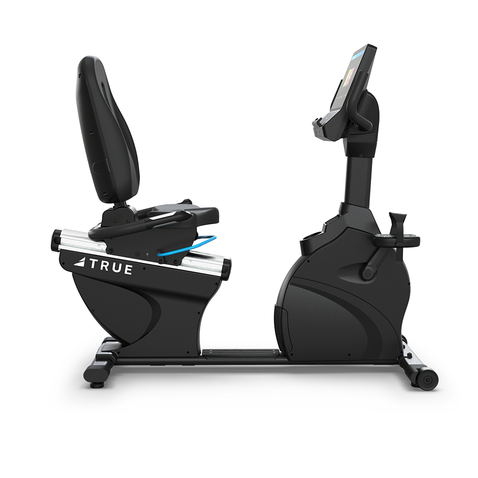 A side view of a black recumbent exercise bike with a cushioned seat, backrest, pedal straps, and a digital display screen, set against a plain white background. The brand TRUE is visible on the frame.