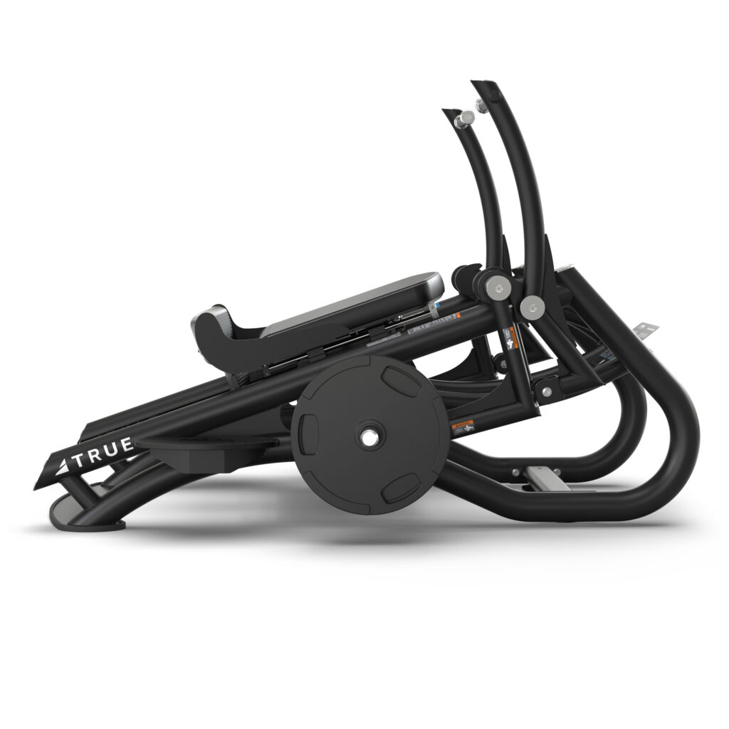 A black leg press machine with padded seat and backrest, angled footplate, and weight plates mounted on the side; the brand name TRUE is visible on the frame.