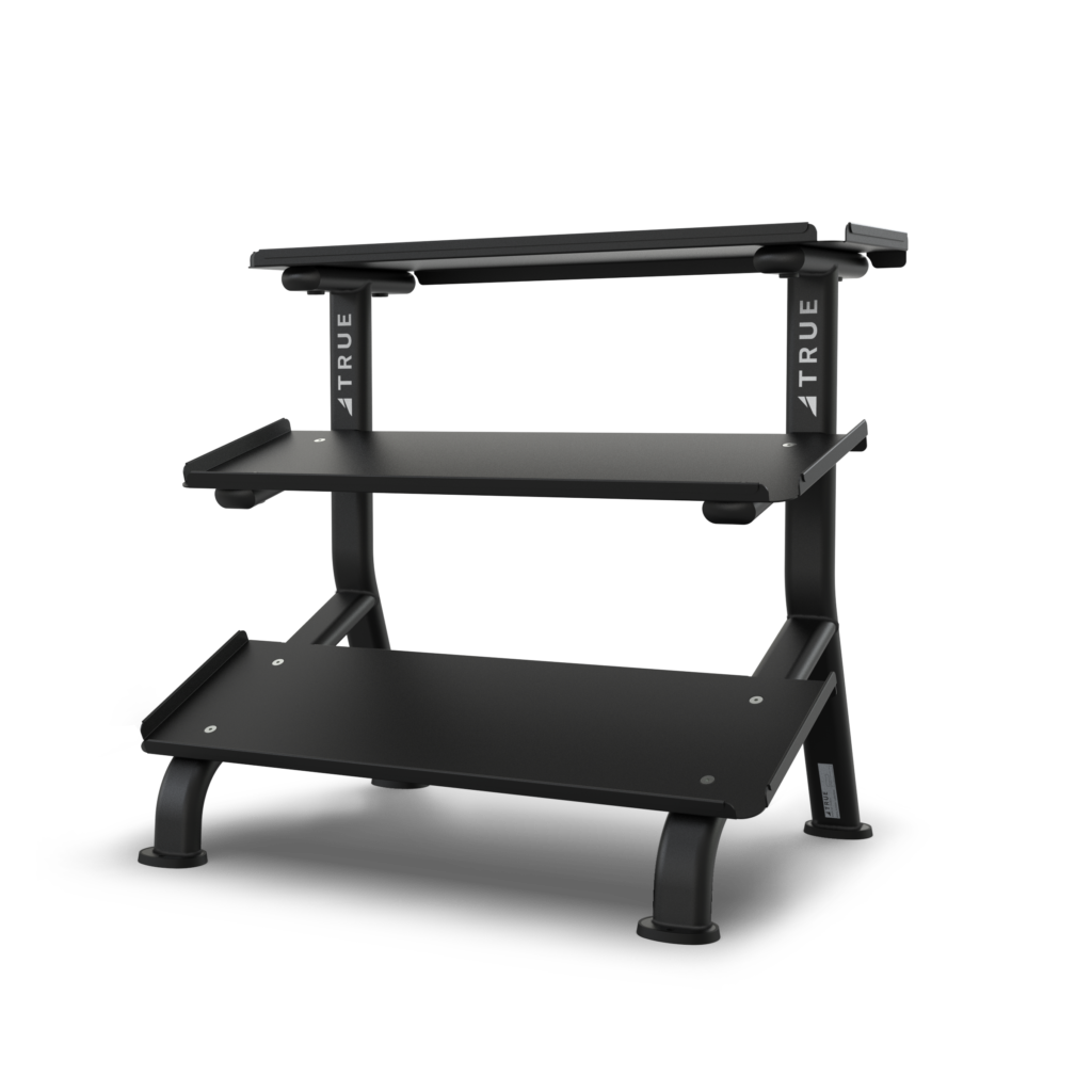 A black, three-tiered storage rack with sturdy metal shelves and tubular legs, designed for organizing fitness accessories or free weights; the word TRUE is printed vertically on the side supports.